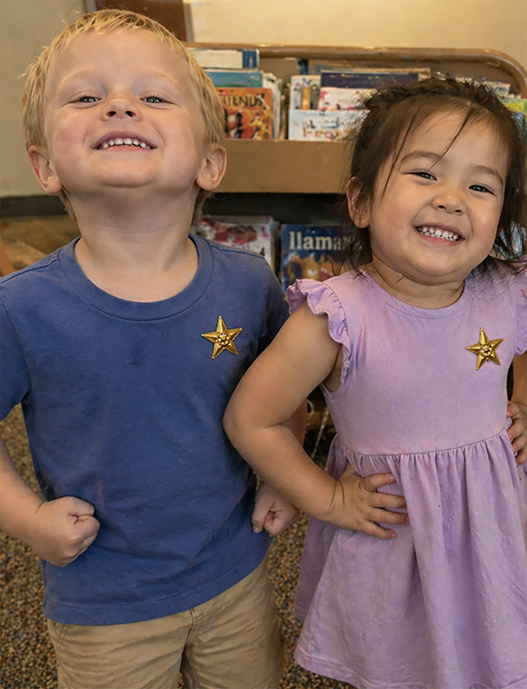 Two children proudly wearing bravery badges, showing confidence after the I AM BRAVE Movement interactive storytime experience.