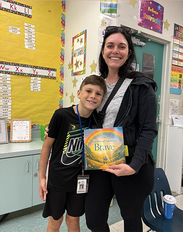 Teacher and 1st grade student holding The Garden of Growing Brave during a school visit, supporting social emotional learning and confidence building in the classroom.