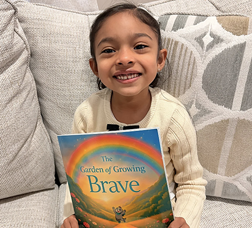 Happy child holding a book called The Garden of Growing Brave that helps prevent meltdowns and supports emotional regulation for toddlers learning to manage big feelings.